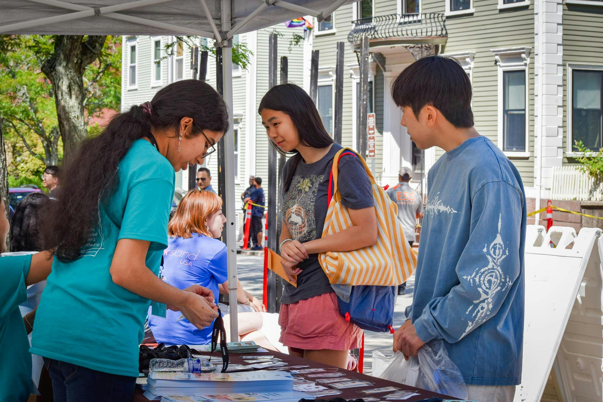 A move-in helper passes out a lanyard to a first-year student.