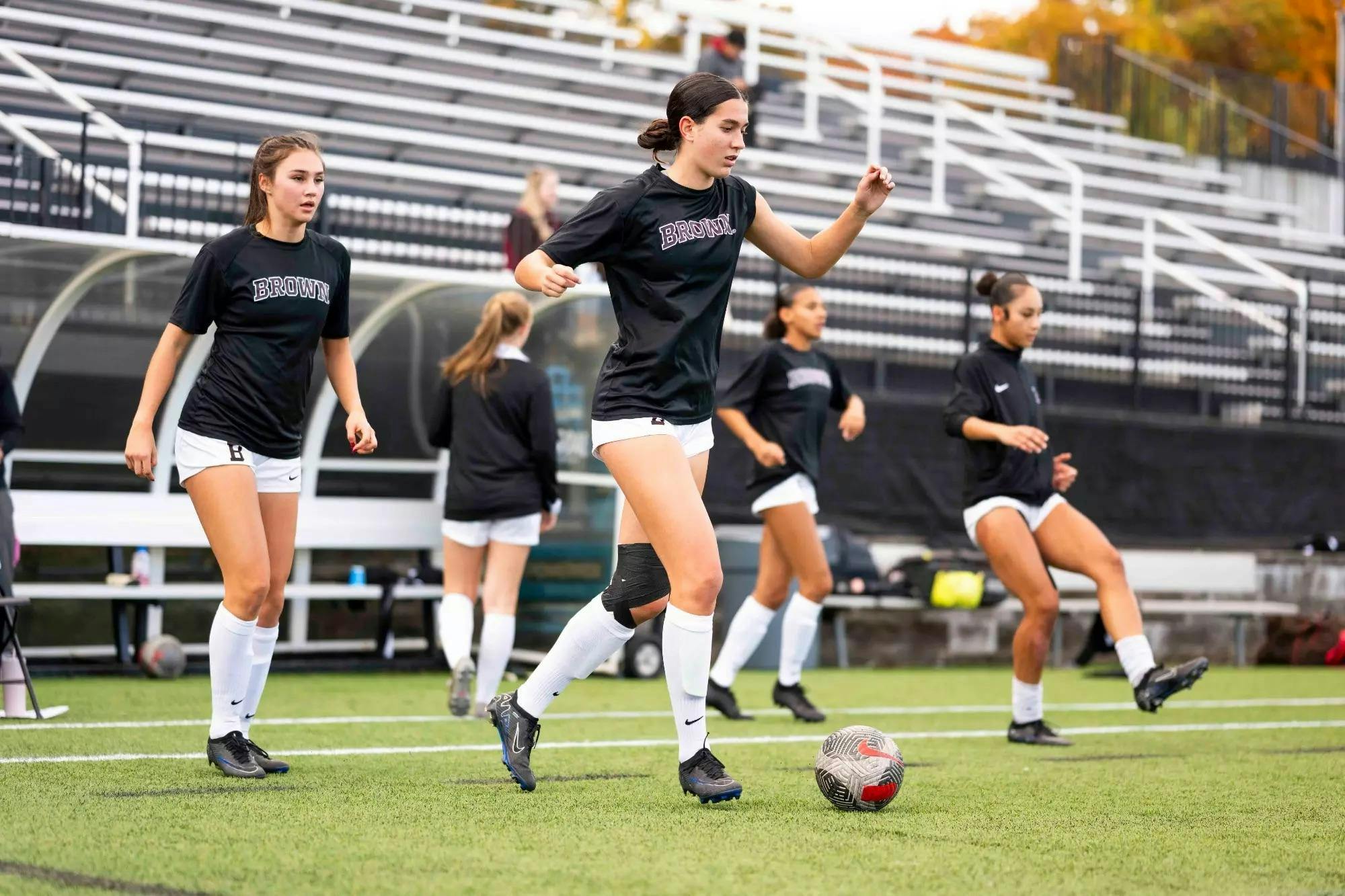Member of Brown women's soccer warming up kicking a ball