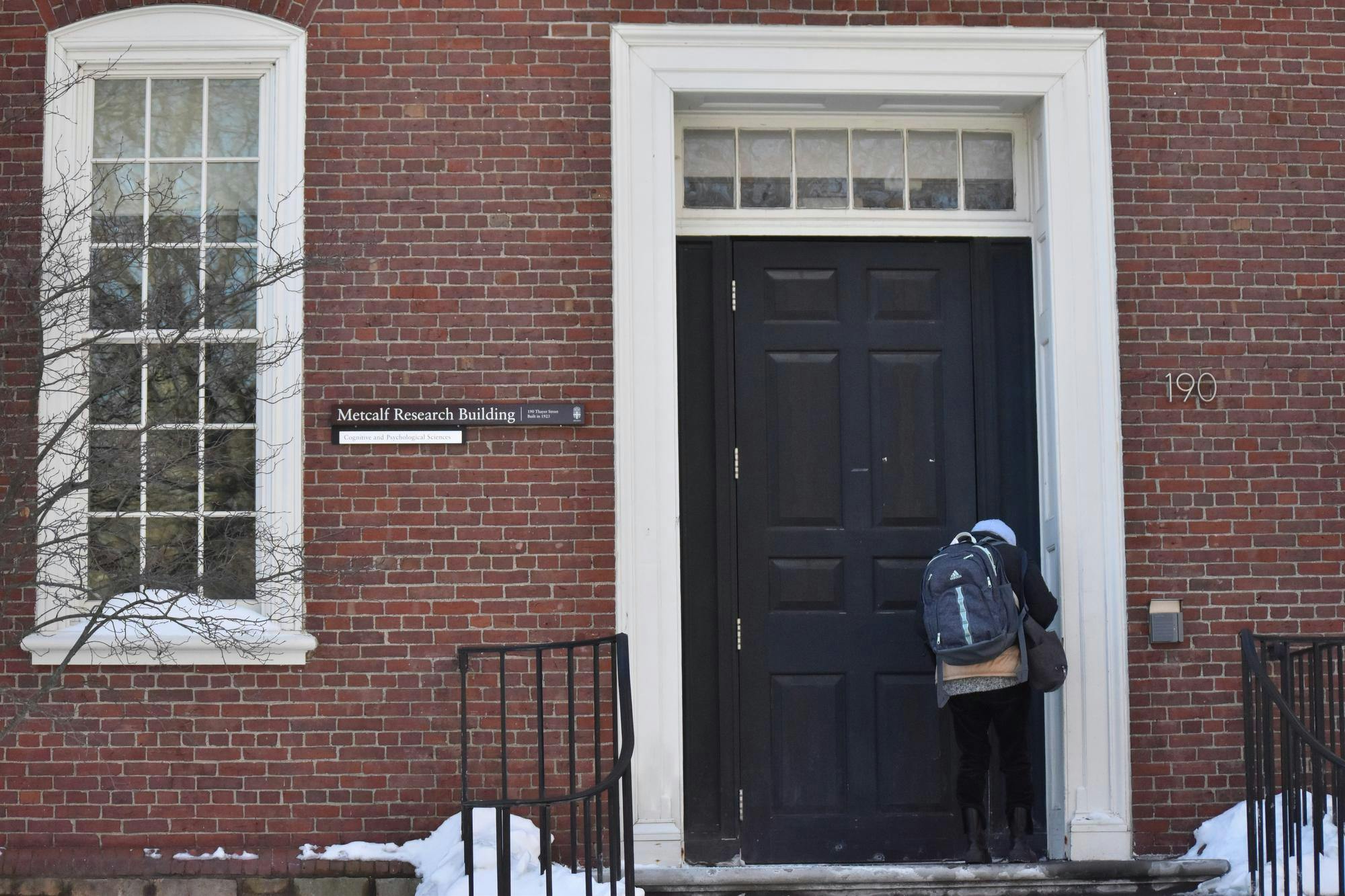 A student entering the Metcalf Research Building on Thayer St.