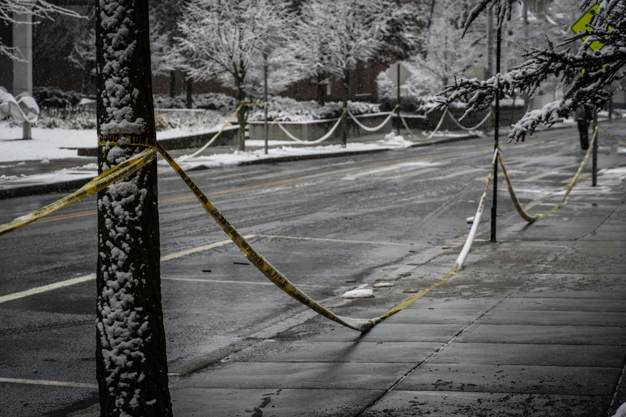 A row of caution tape extending down the street form the univeristy's campus.