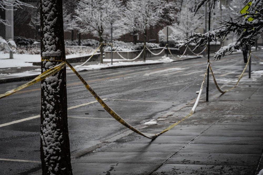 A row of caution tape extending down the street form the univeristy's campus.