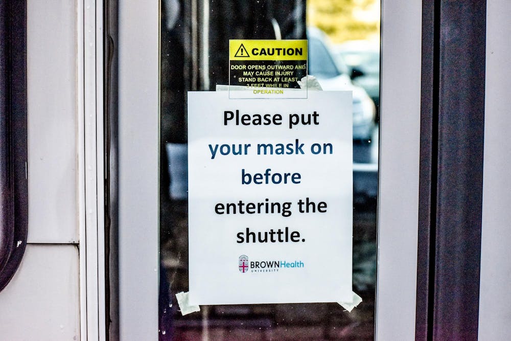 A sign on the door to a  University shuttle bus reads, "Please put a mask on before entering the shuttle."