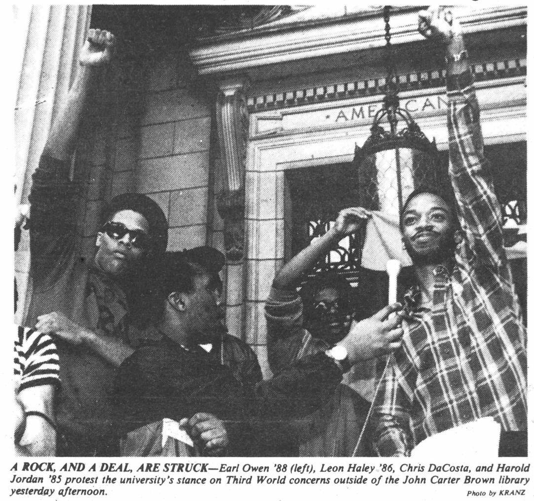 Four men stand outside the John Carter Brown Library, protesting in a black-and-white Herald photo from the 1980s. 

