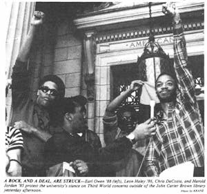 Four men stand outside the John Carter Brown Library, protesting in a black-and-white Herald photo from the 1980s.