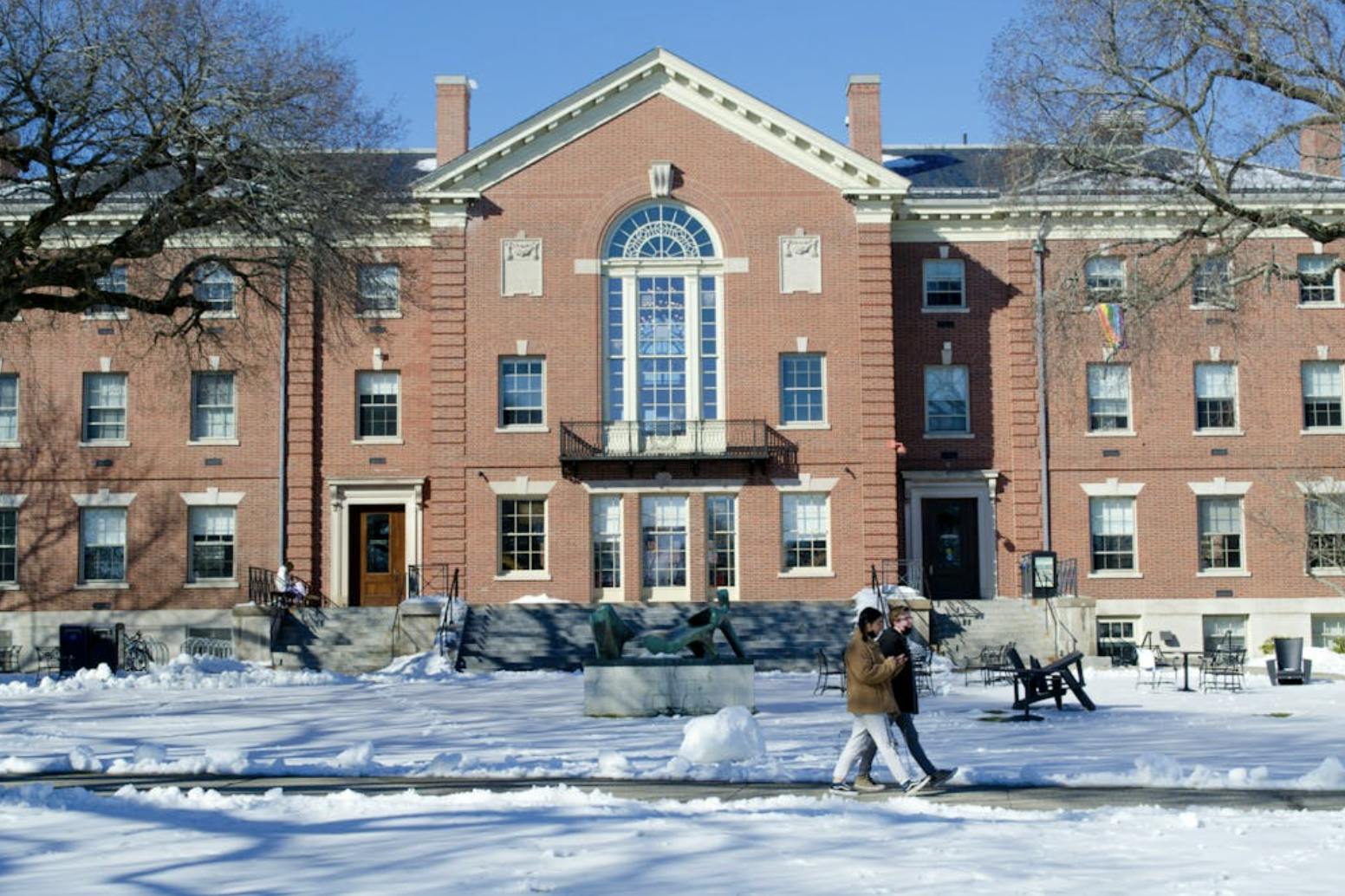 A photo of Stephen Robert '62 Campus Center with two people walking in front of the building. The ground is covered with snow.
