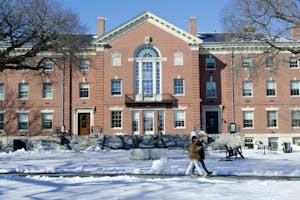 A photo of Stephen Robert '62 Campus Center with two people walking in front of the building. The ground is covered with snow.