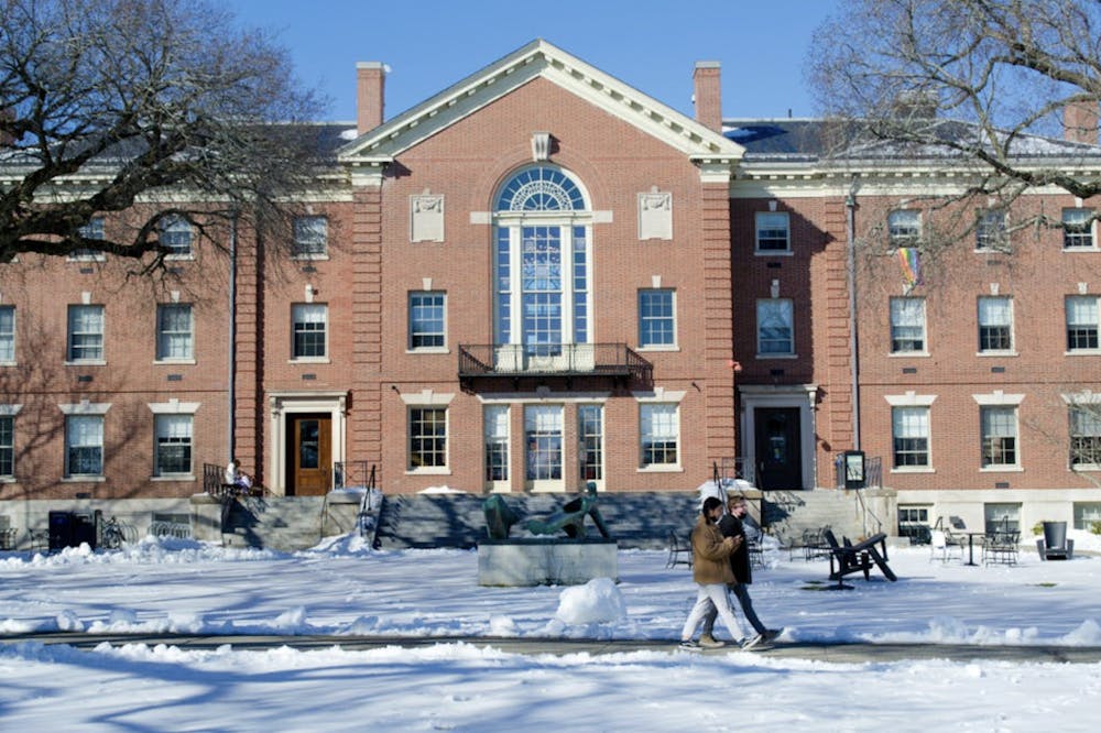 A photo of Stephen Robert '62 Campus Center with two people walking in front of the building. The ground is covered with snow.