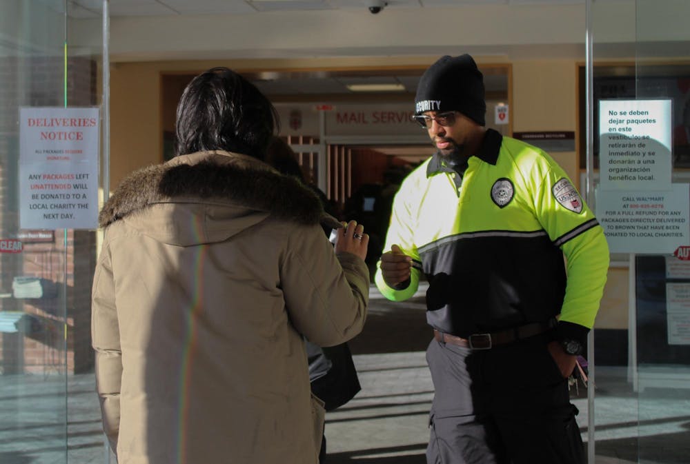 Campus security officer checking a student’s ID at the entrance of Page-Robinson Hall.