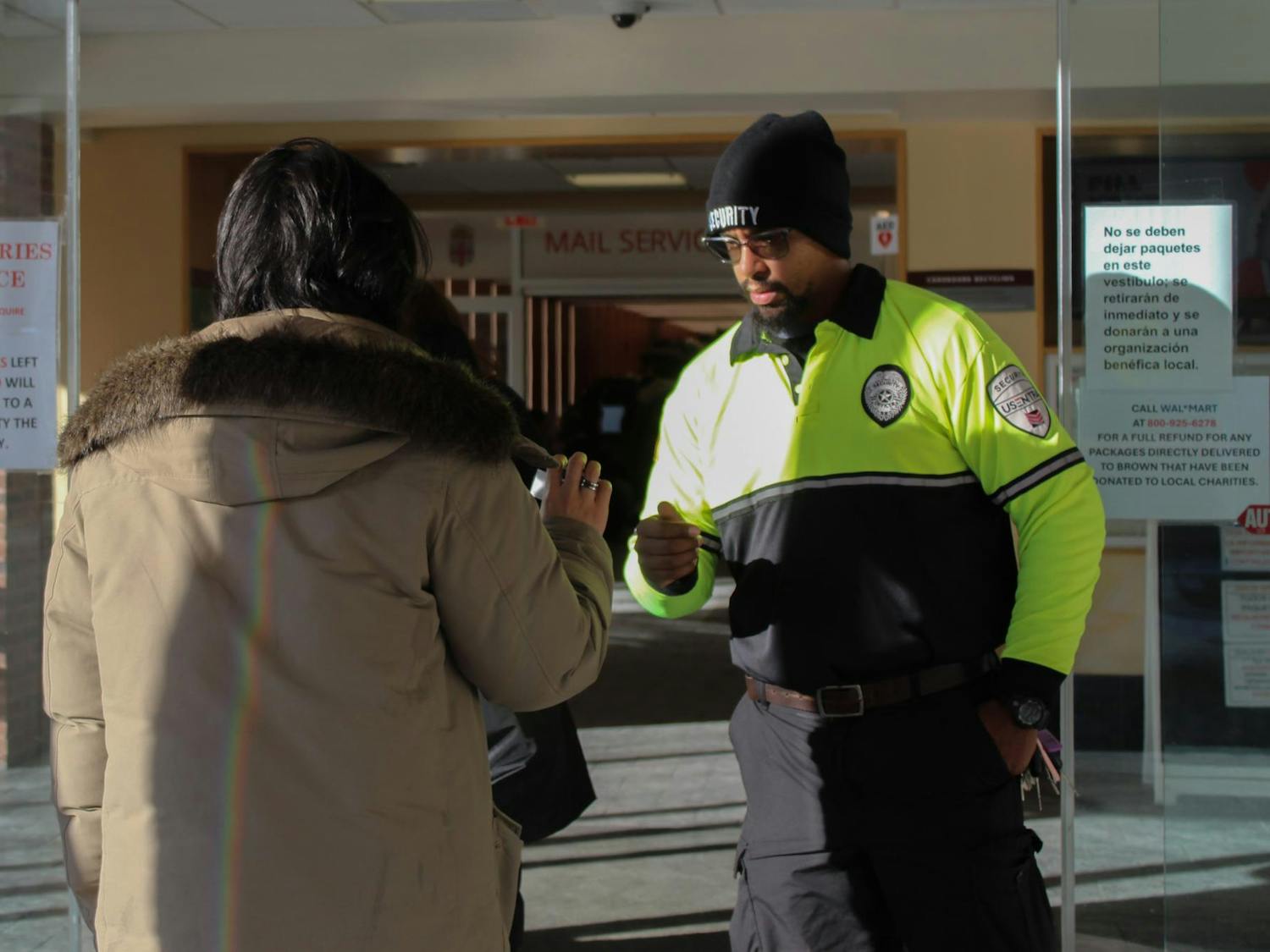 Campus security officer checking a student’s ID at the entrance of Page-Robinson Hall.