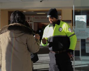 Campus security officer checking a student’s ID at the entrance of Page-Robinson Hall.