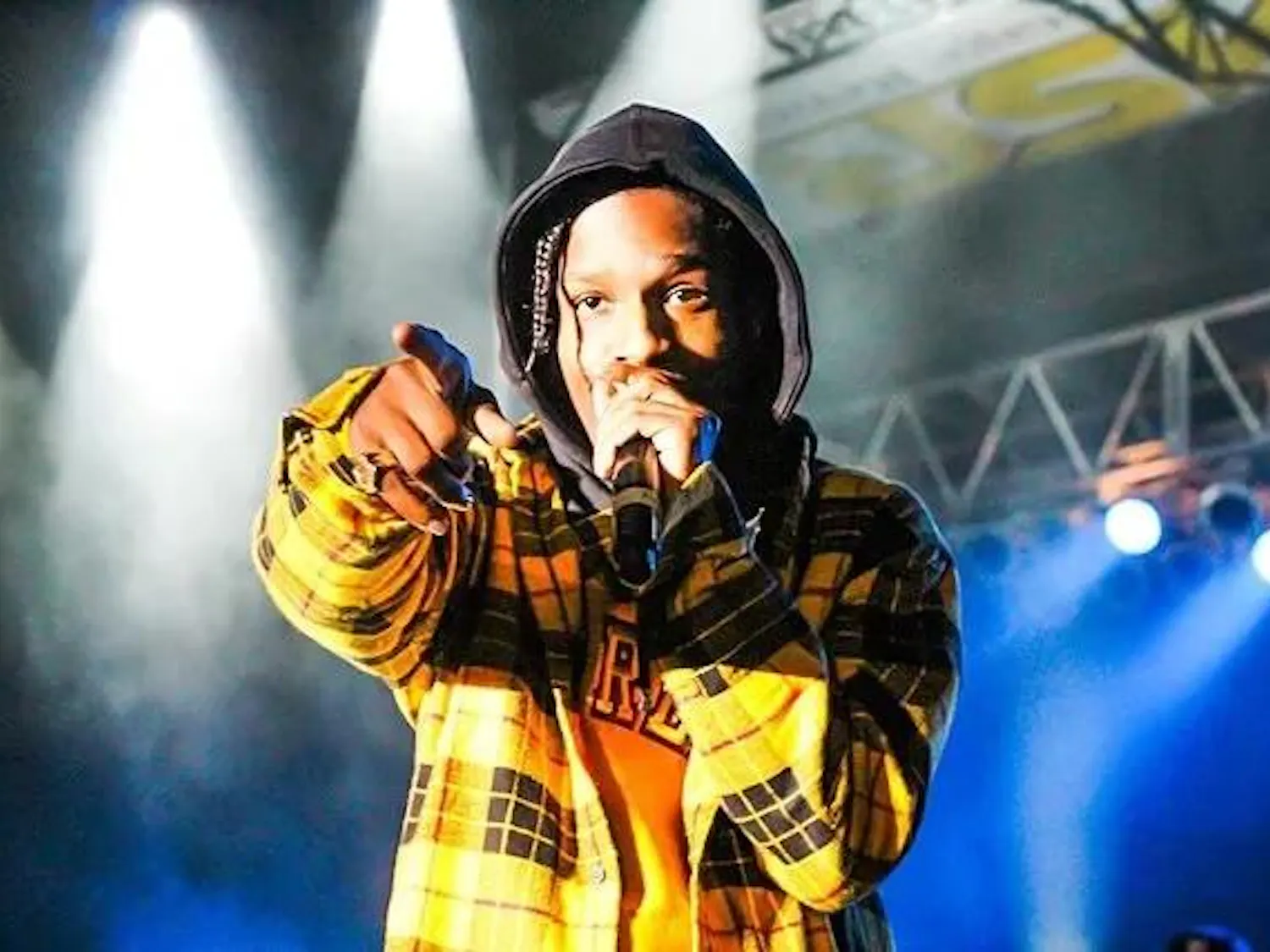 Photo of A$AP Rocky performing at a concert venue, pointing past the camera.