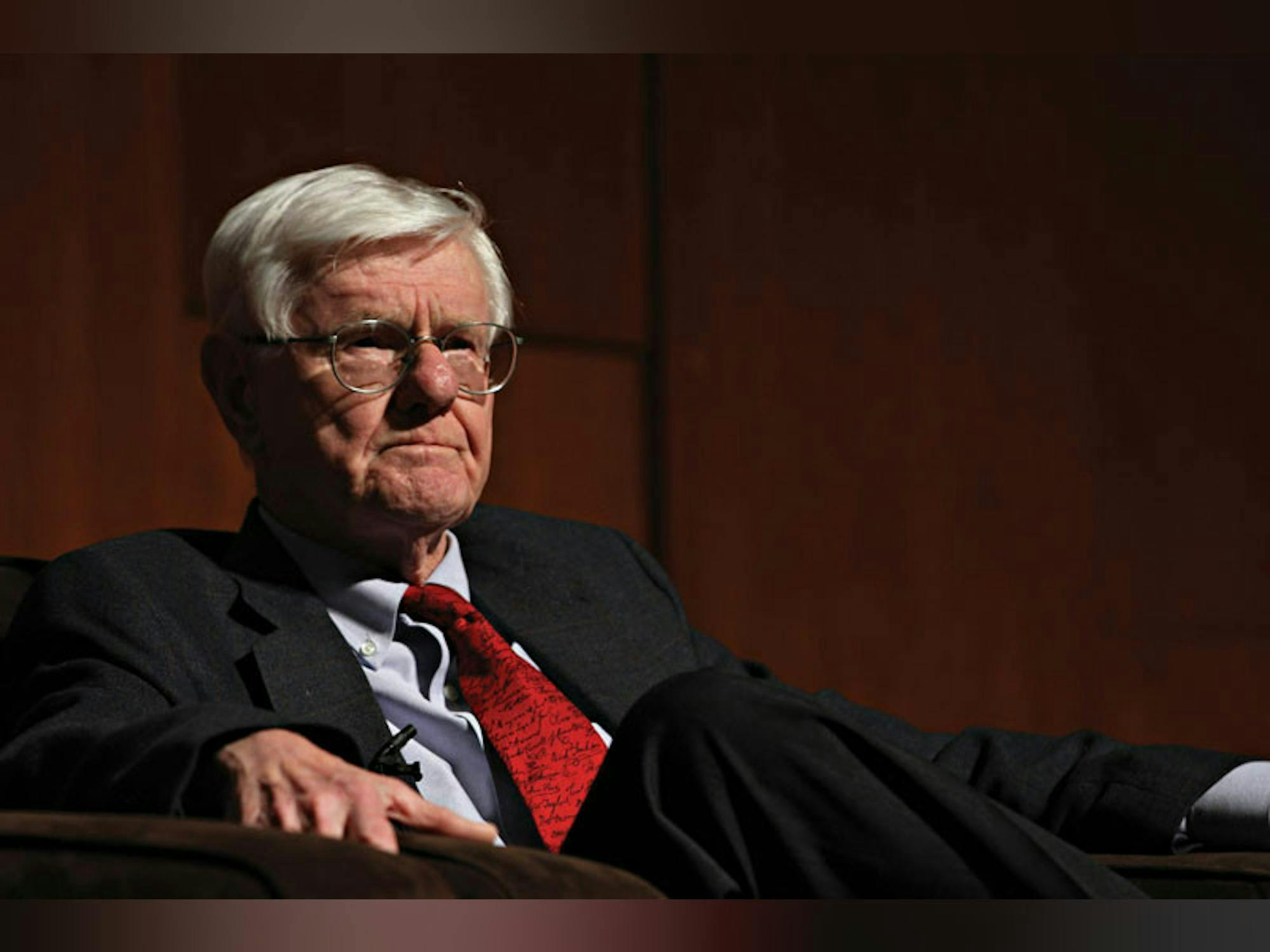Gordon Wood sits in a grey suit in front of a red wood background.