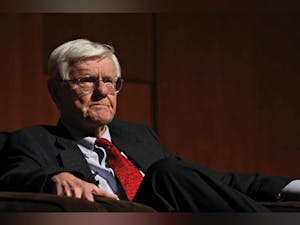 Gordon Wood sits in a grey suit in front of a red wood background.