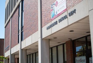 The Providence Public School Department building, a brick building with with words Providence School Dept on concrete on the building.