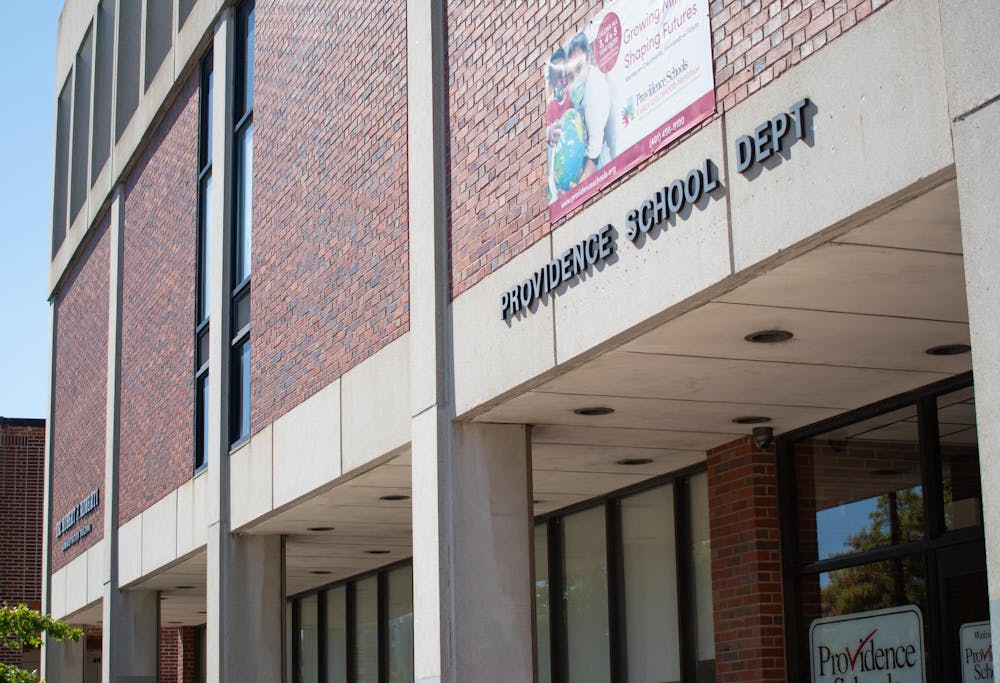 The Providence Public School Department building, a brick building with with words Providence School Dept on concrete on the building.