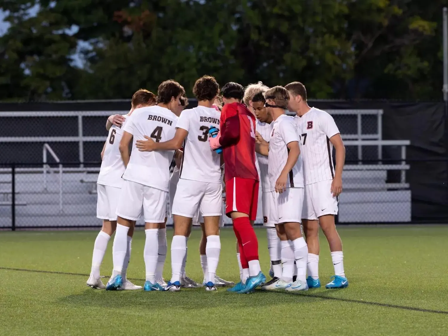 Members of Brown's mens soccer team huddle on the field