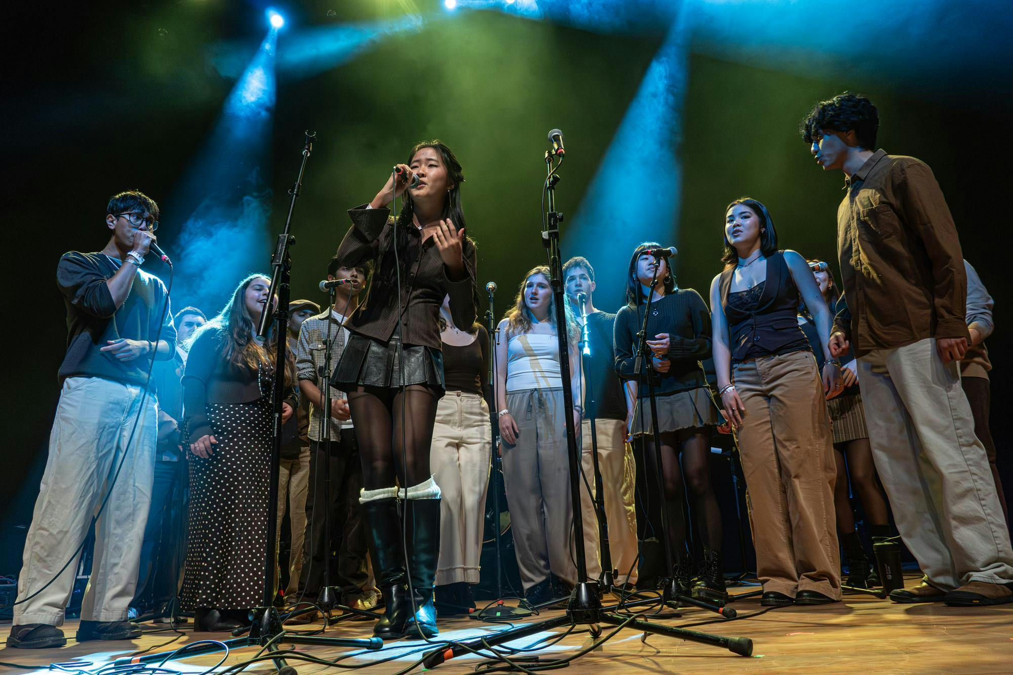 The Jabberwocks, a large student a capella group, surround 3 microphones.  

