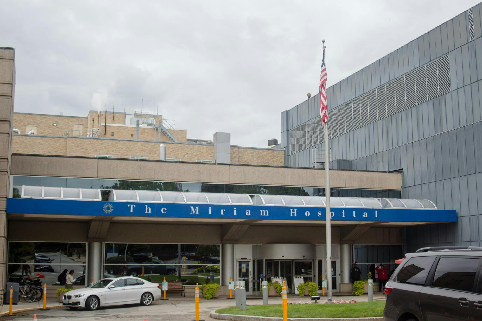 A car sits parked in front of the entryway of The Miriam Hospital in Providence on a cloudy day.