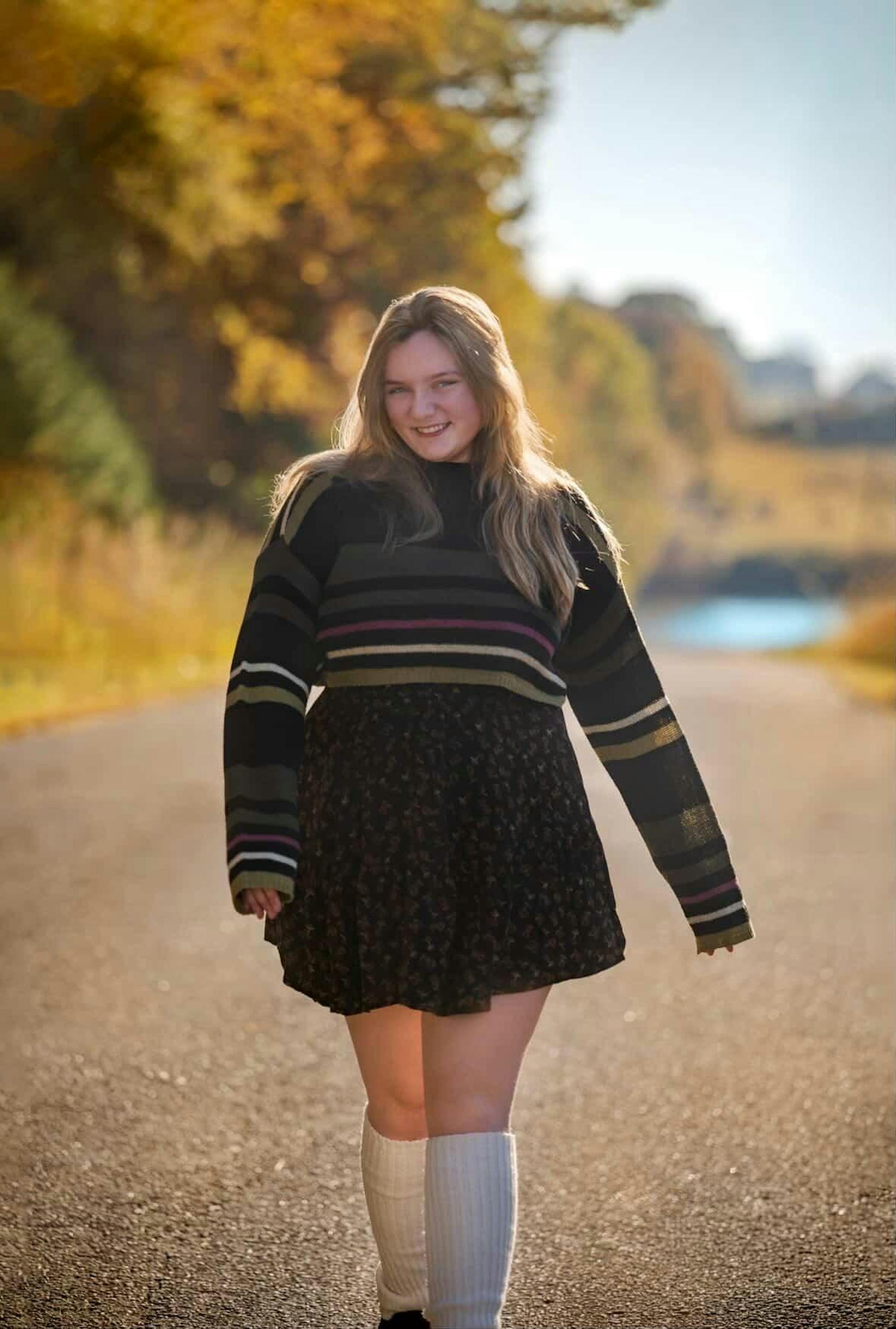 A blonde girl in a sweater walking toward the camera. 