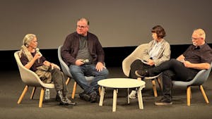 Sally Mann sits on stage with microphone along with three other speakers.