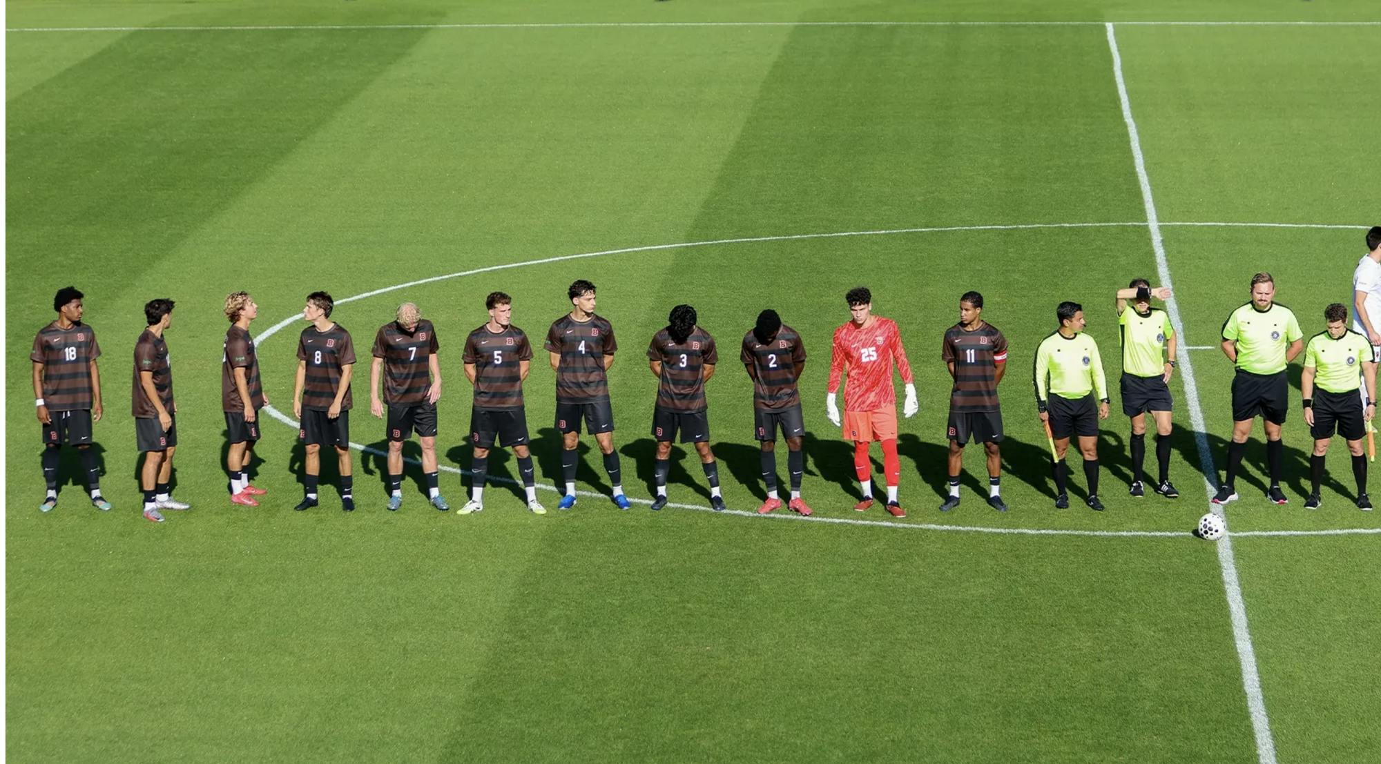 Soccer players in a line during starting lineup announcements. They look hopeful, unaware of what's to come.