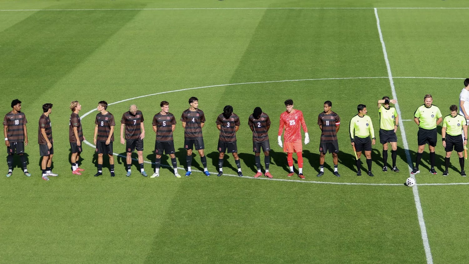 Soccer players in a line during starting lineup announcements. They look hopeful, unaware of what's to come.