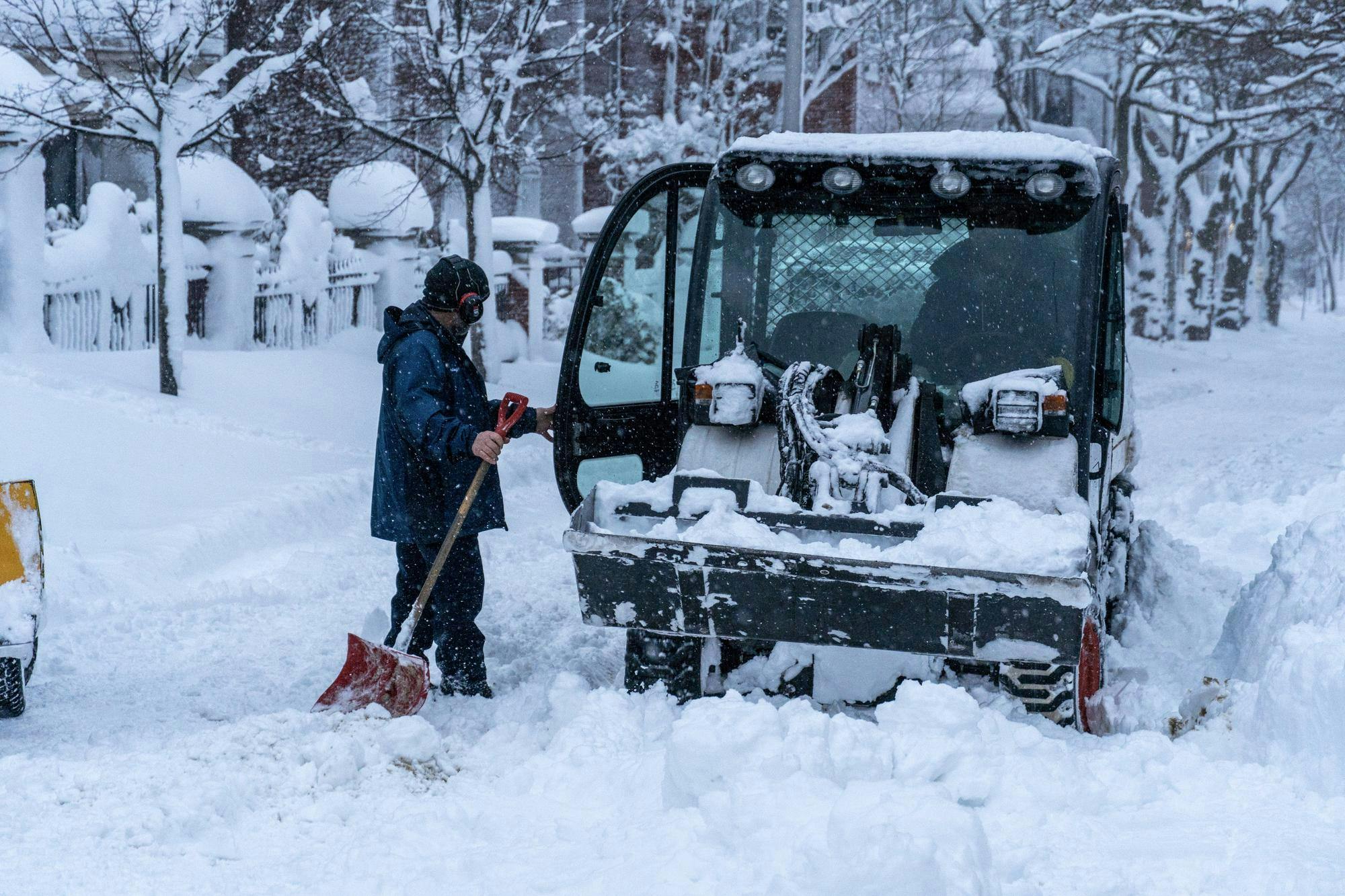 A photo of a car in the street with a person holding a shovel opening its door.