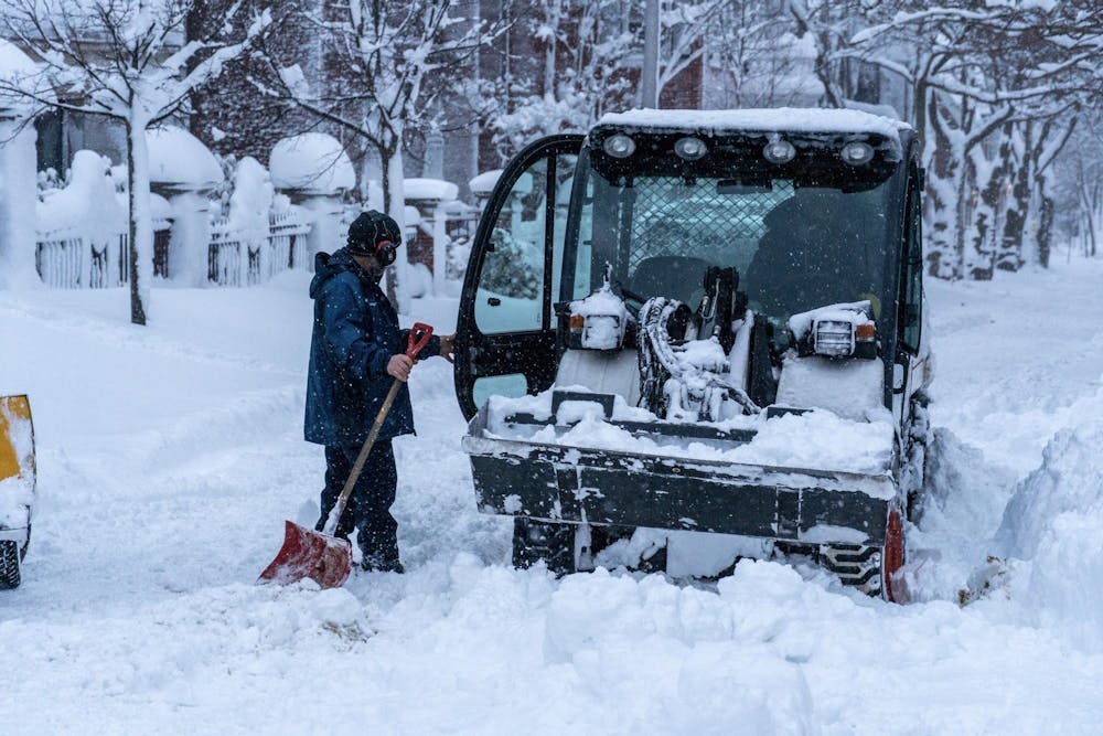 A photo of a car in the street with a person holding a shovel opening its door.