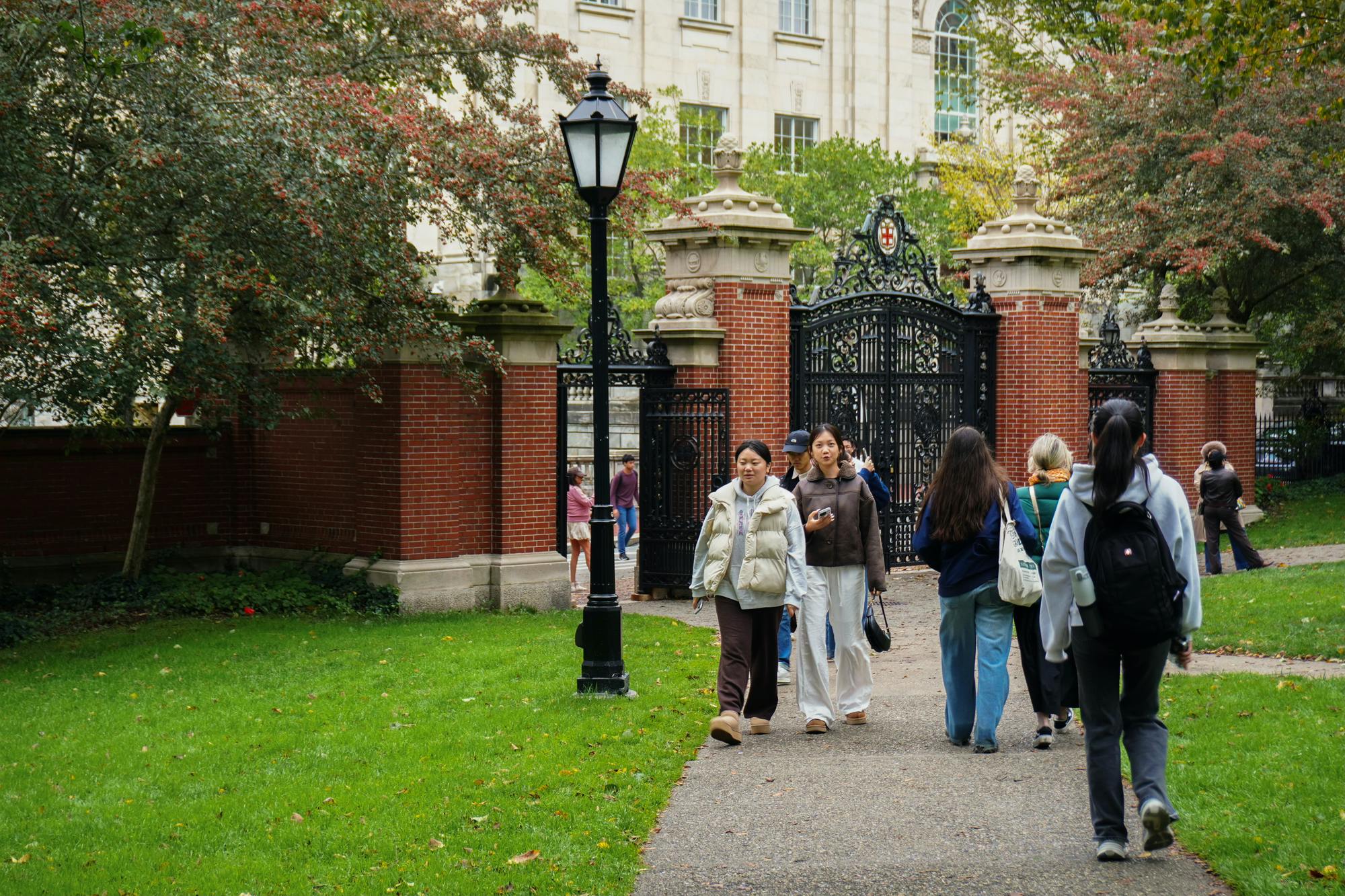 People walking next to the main green in front of the Van Wickle Gates