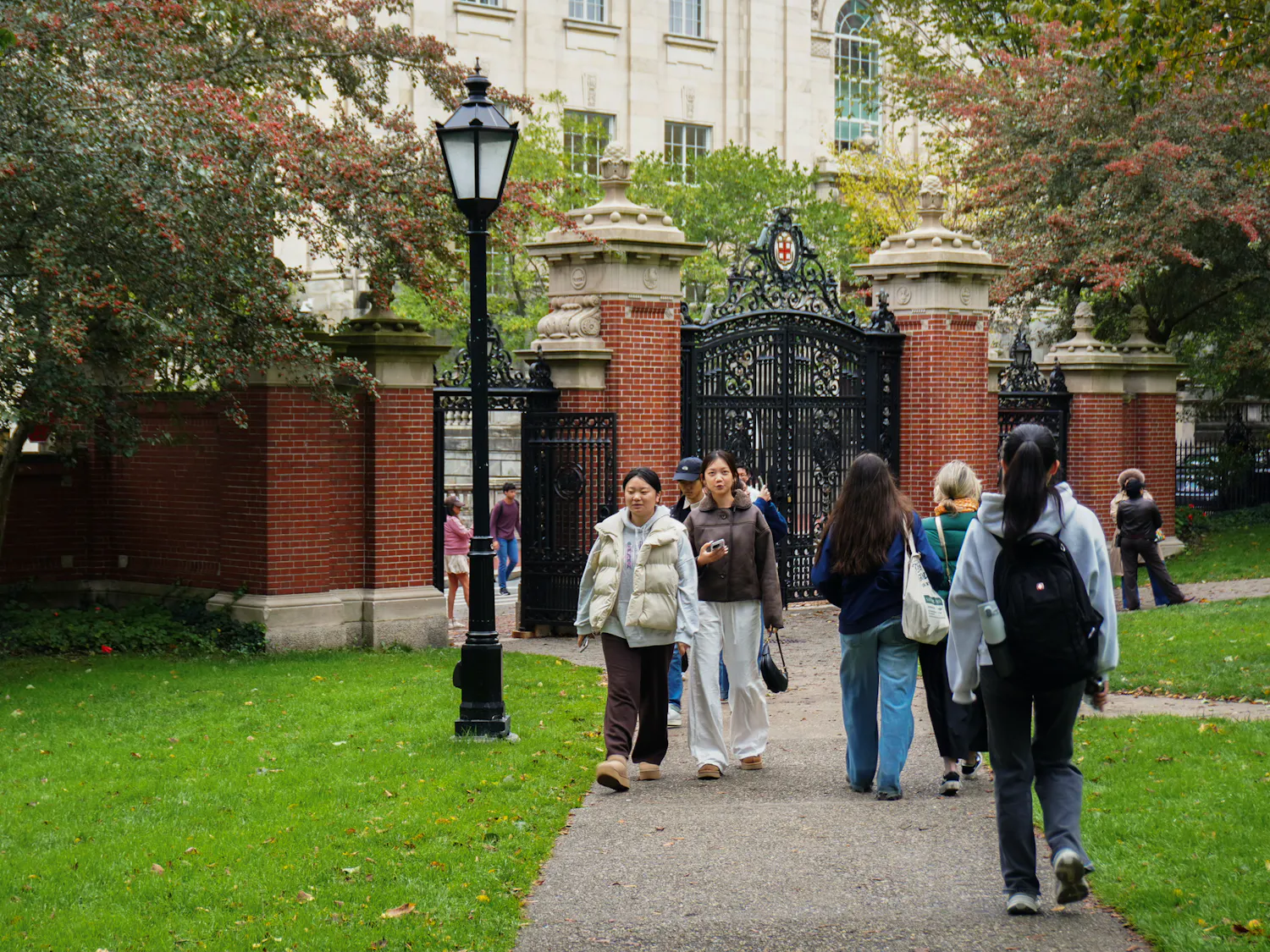 People walking next to the main green in front of the Van Wickle Gates