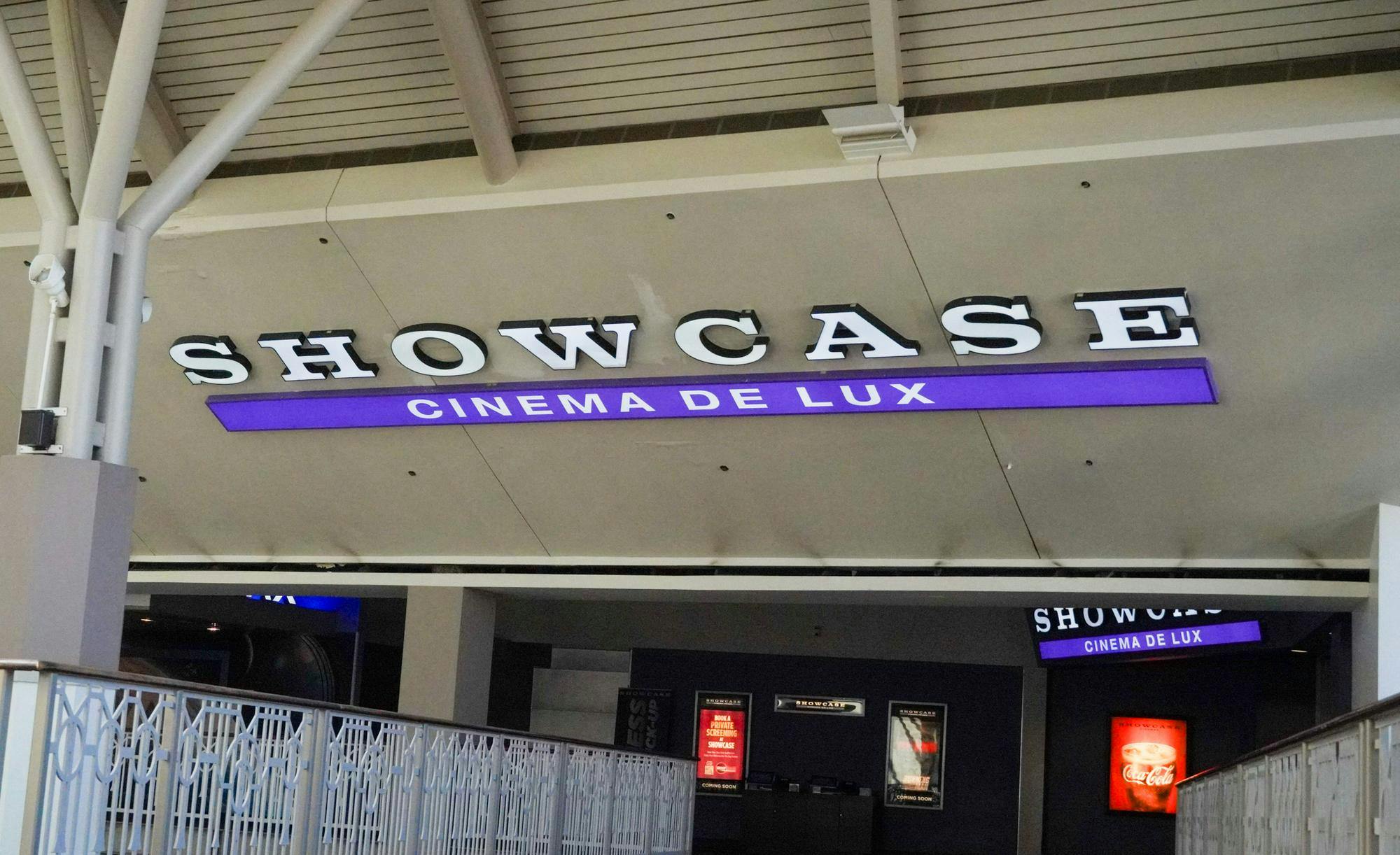 Slanted concrete slab with words "Showcase" in all-caps and white lighted letters. In a purple lighted rectangle bar right below "Showcase" are the words "Cinema de Lux" in all-caps as well.