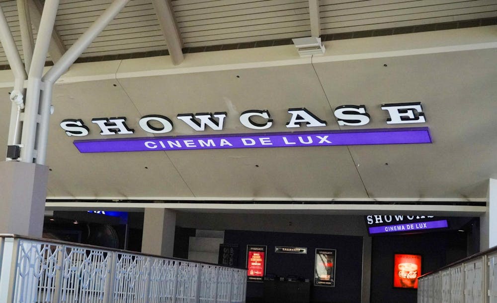 Slanted concrete slab with words "Showcase" in all-caps and white lighted letters. In a purple lighted rectangle bar right below "Showcase" are the words "Cinema de Lux" in all-caps as well.