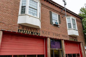 An image of a red brick building with bright red garages and an American flag in the window. A sign on the building reads “Providence Fire Department."