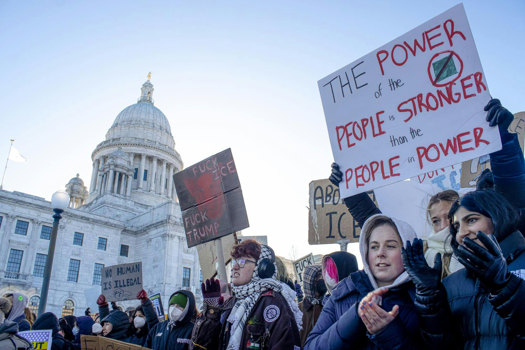 A crowd of protesters cheer in front of the State House.
