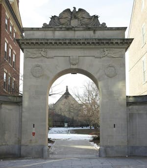 Photo shows archway that opens up onto a snow-covered quiet green. 