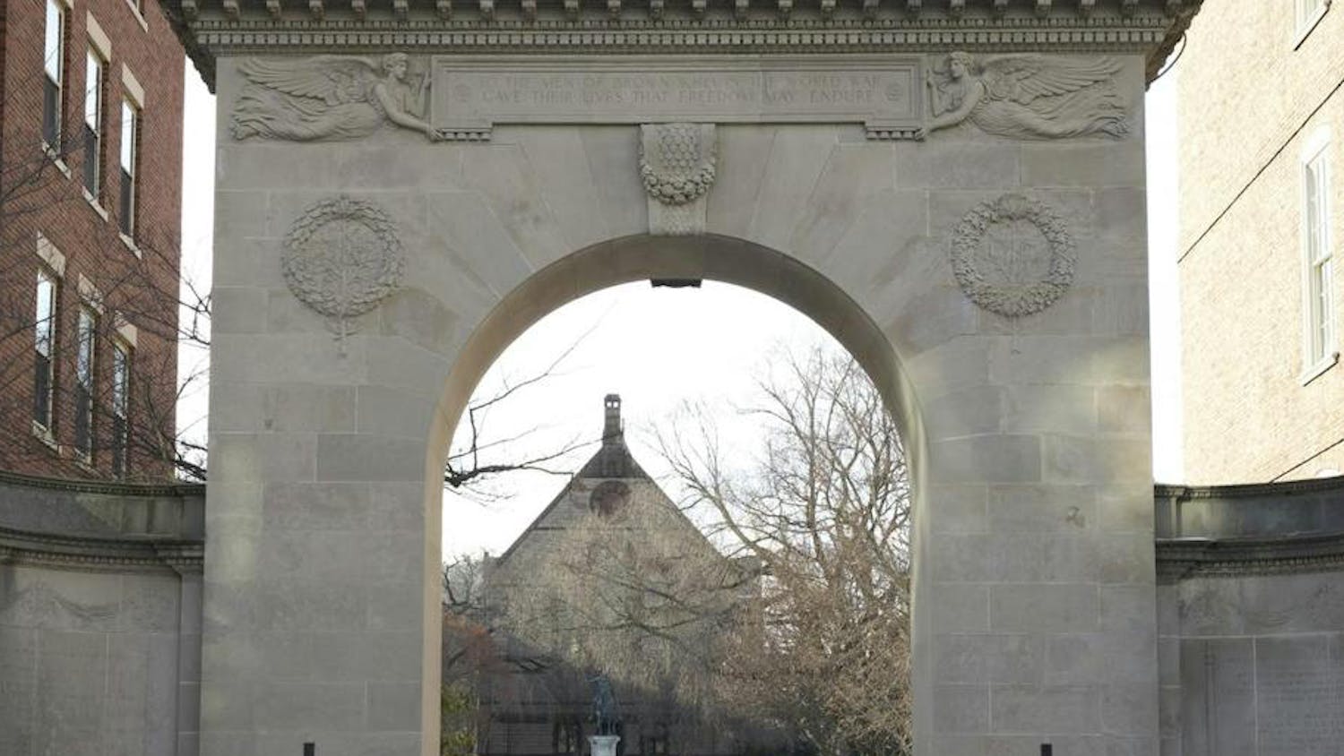 Photo shows archway that opens up onto a snow-covered quiet green.