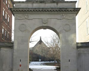 Photo shows archway that opens up onto a snow-covered quiet green.