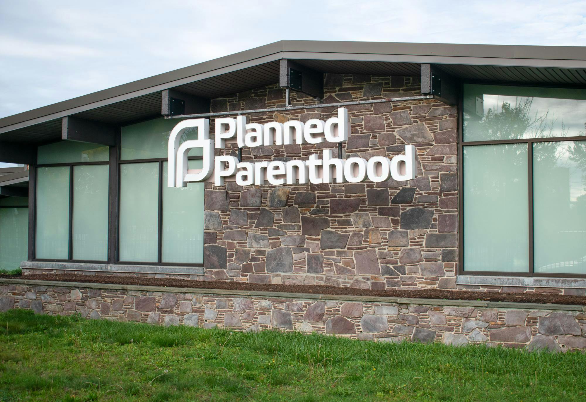 One-story brick building with the words "Planned Parenthood" in large white letter hanging off a metal bar in front. 