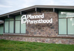 One-story brick building with the words "Planned Parenthood" in large white letter hanging off a metal bar in front. 
