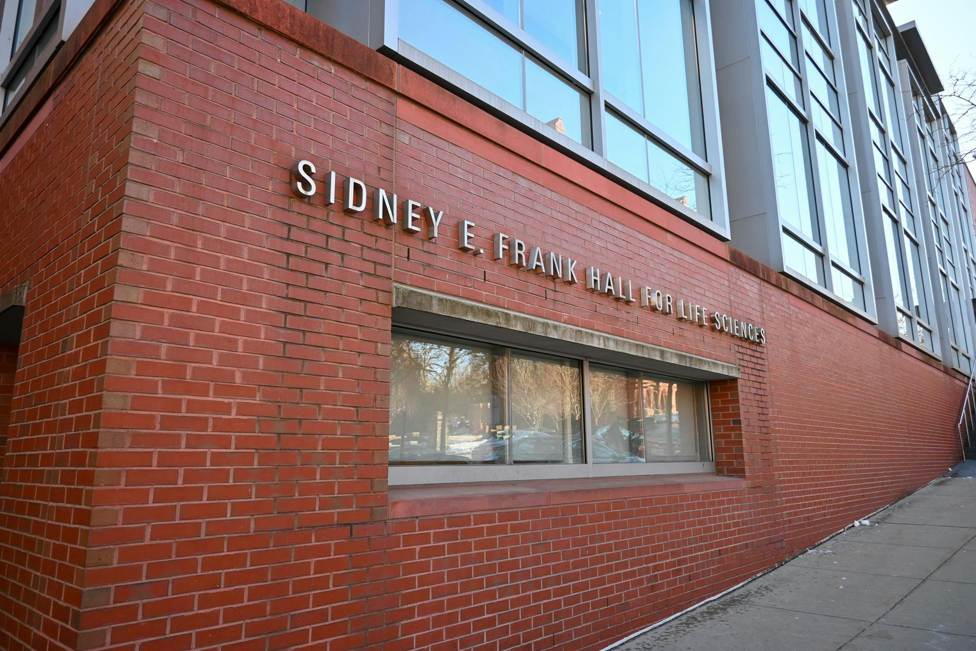 A photo of the Sidney E. Frank Life Sciences Building — a large, brick building with its name written in silver letters across the side.