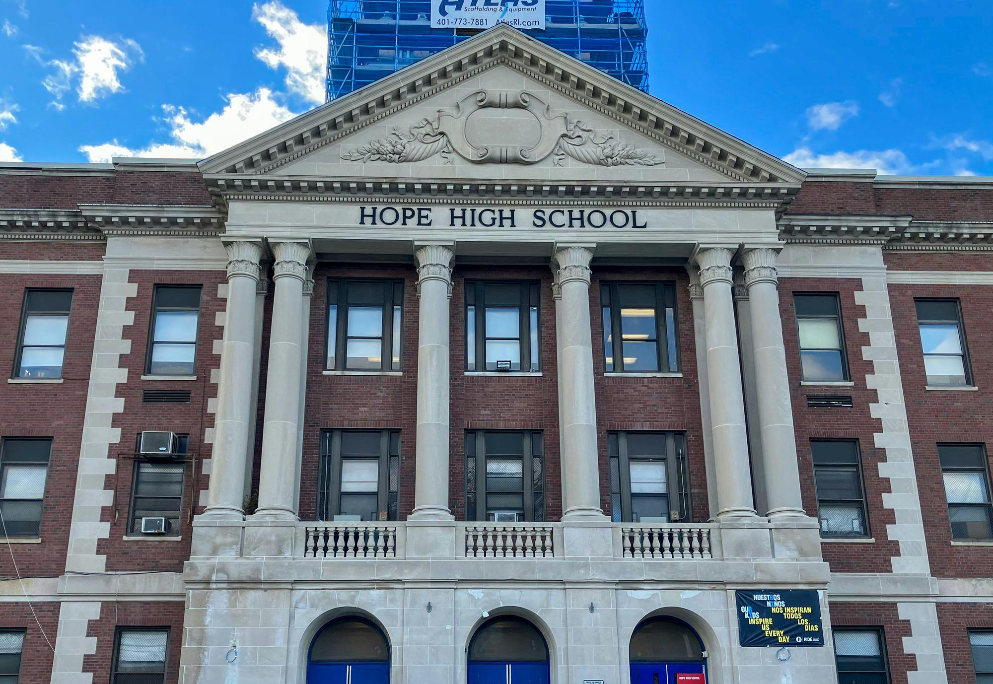 A brick building with large white columns. In black text on the front of the building are the words "Hope High School."