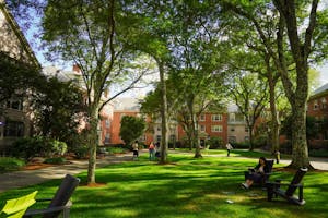 Students scattered among a green quad with dormitory housing surrounding it. 