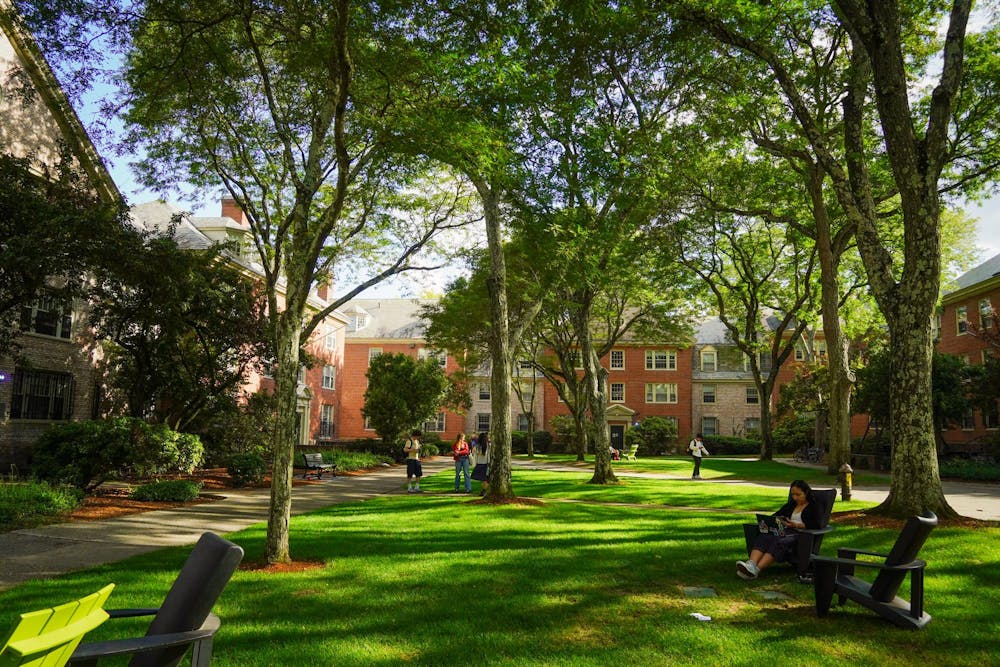 Students scattered among a green quad with dormitory housing surrounding it. 