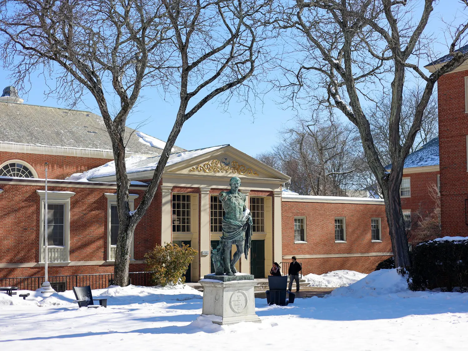 Photo of the Caesar Augustus statue outside the Sharpe Refectory during a sunny day with clear skies and snow on the ground.