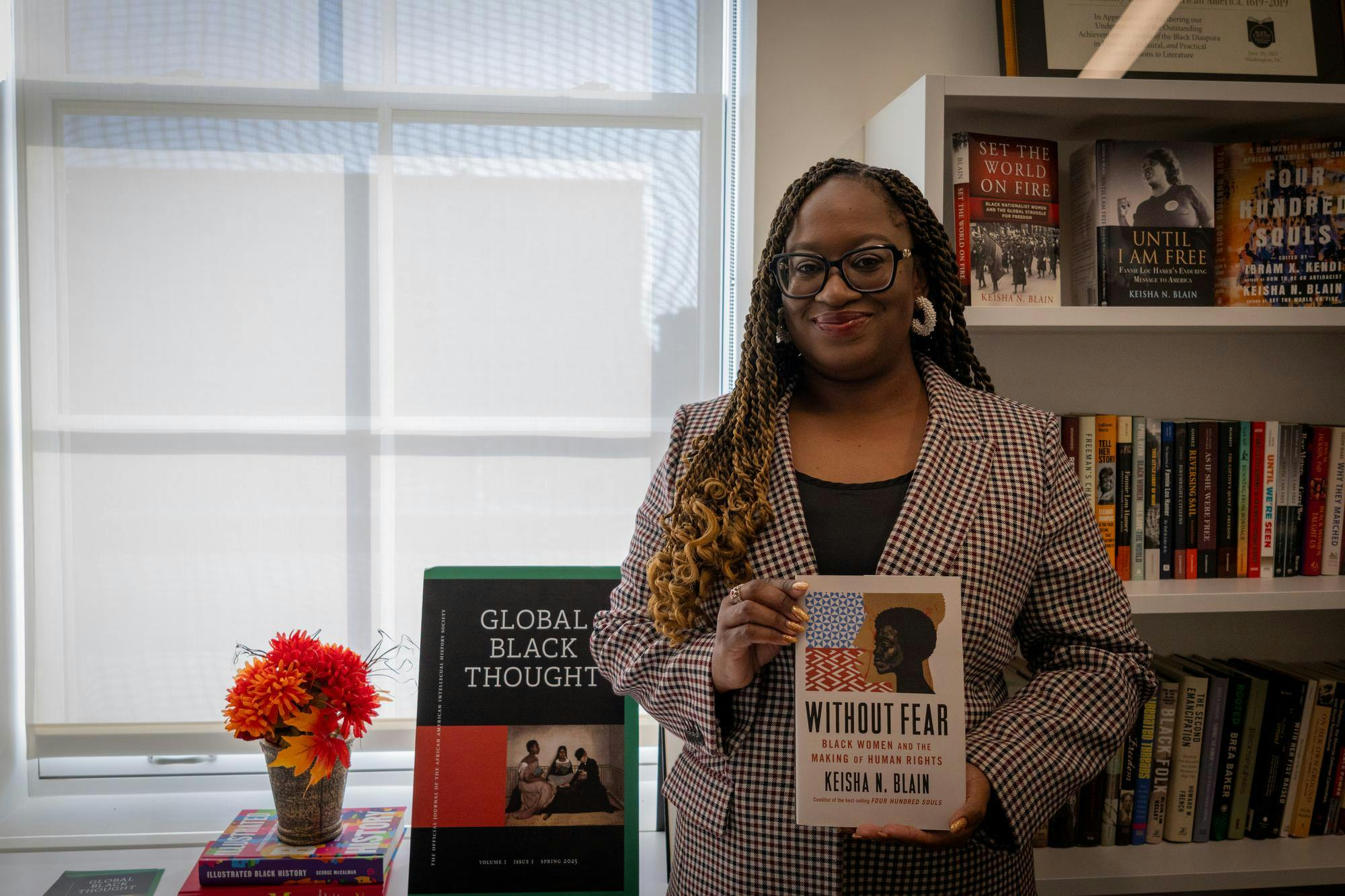 Photo of Professor Keisha Blain posing in front of book shelf with her new book, “Without Fear.”