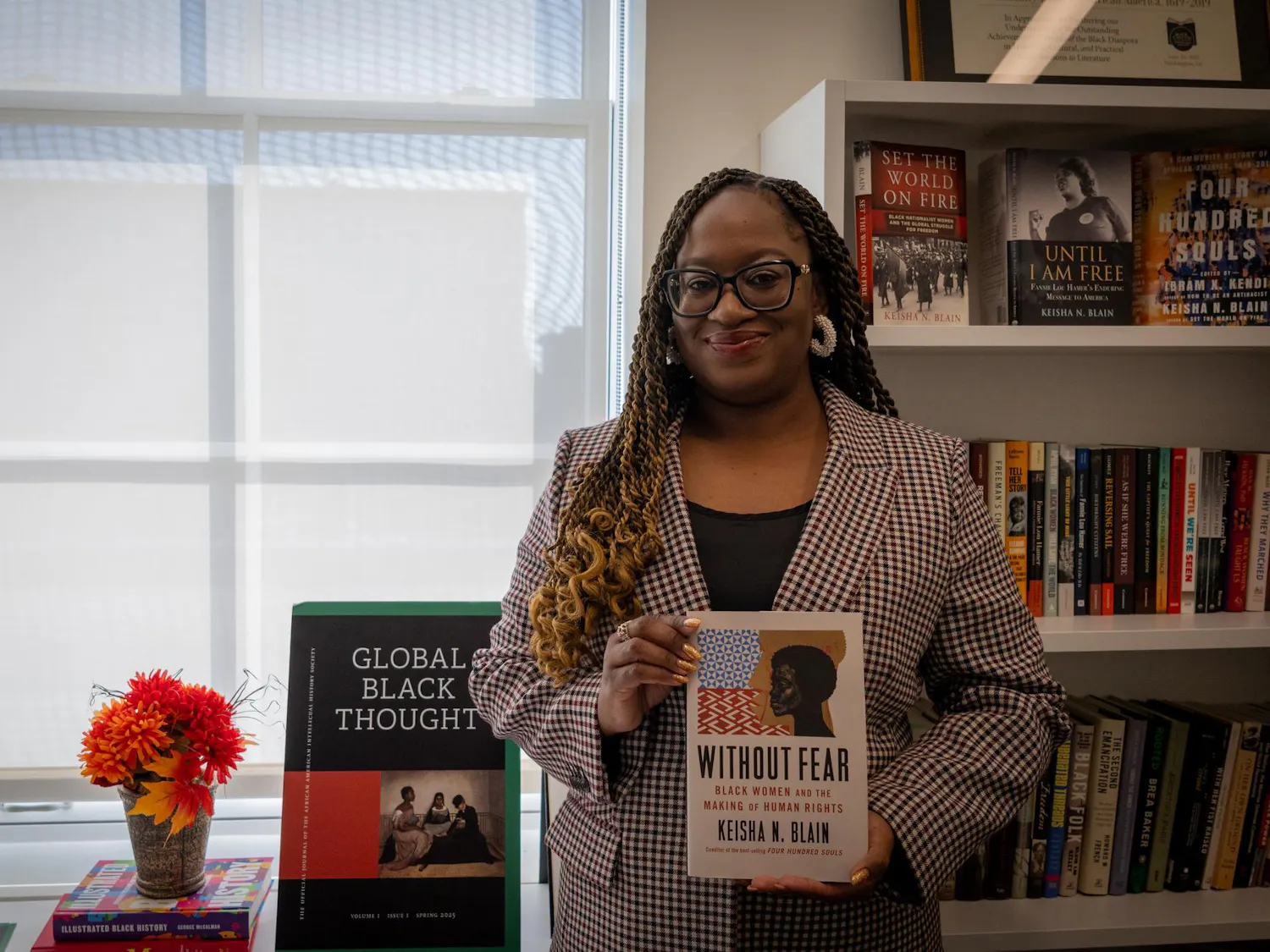 Photo of Professor Keisha Blain posing in front of book shelf with her new book, “Without Fear.”