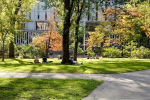 Several students sit on Quiet Green across from the Rockefeller Library, reading and working. 