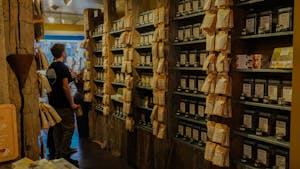 A person stands facing shelves of teas and packets hung off of wooden pillars 