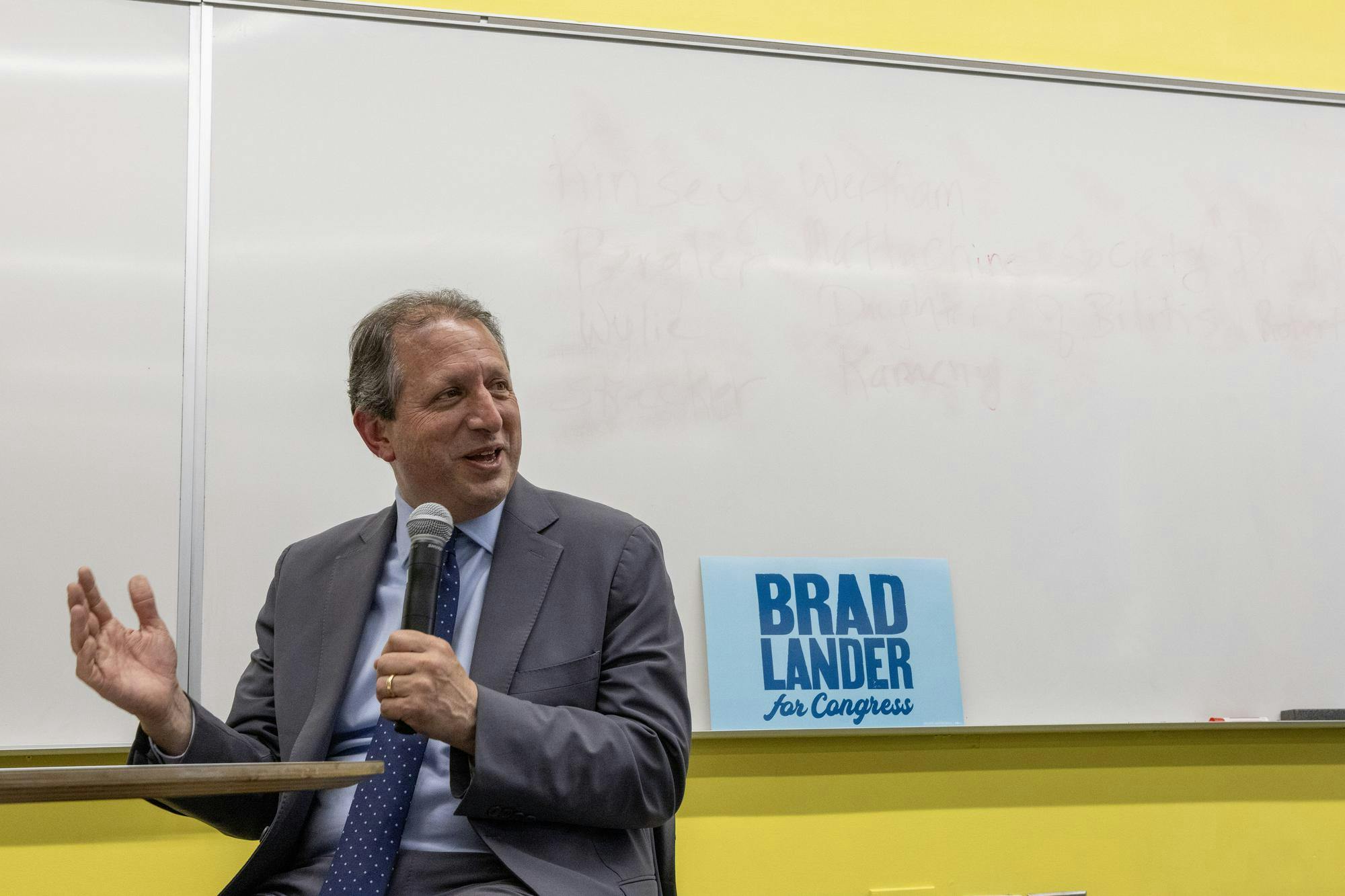 A photo of Brad Lander speaking into a microphone. A sign behind him reads “Brad Lander for Congress.”