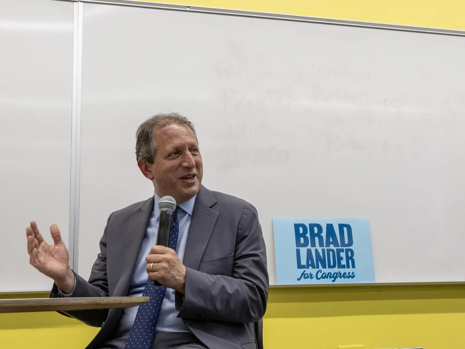 A photo of Brad Lander speaking into a microphone. A sign behind him reads “Brad Lander for Congress.”